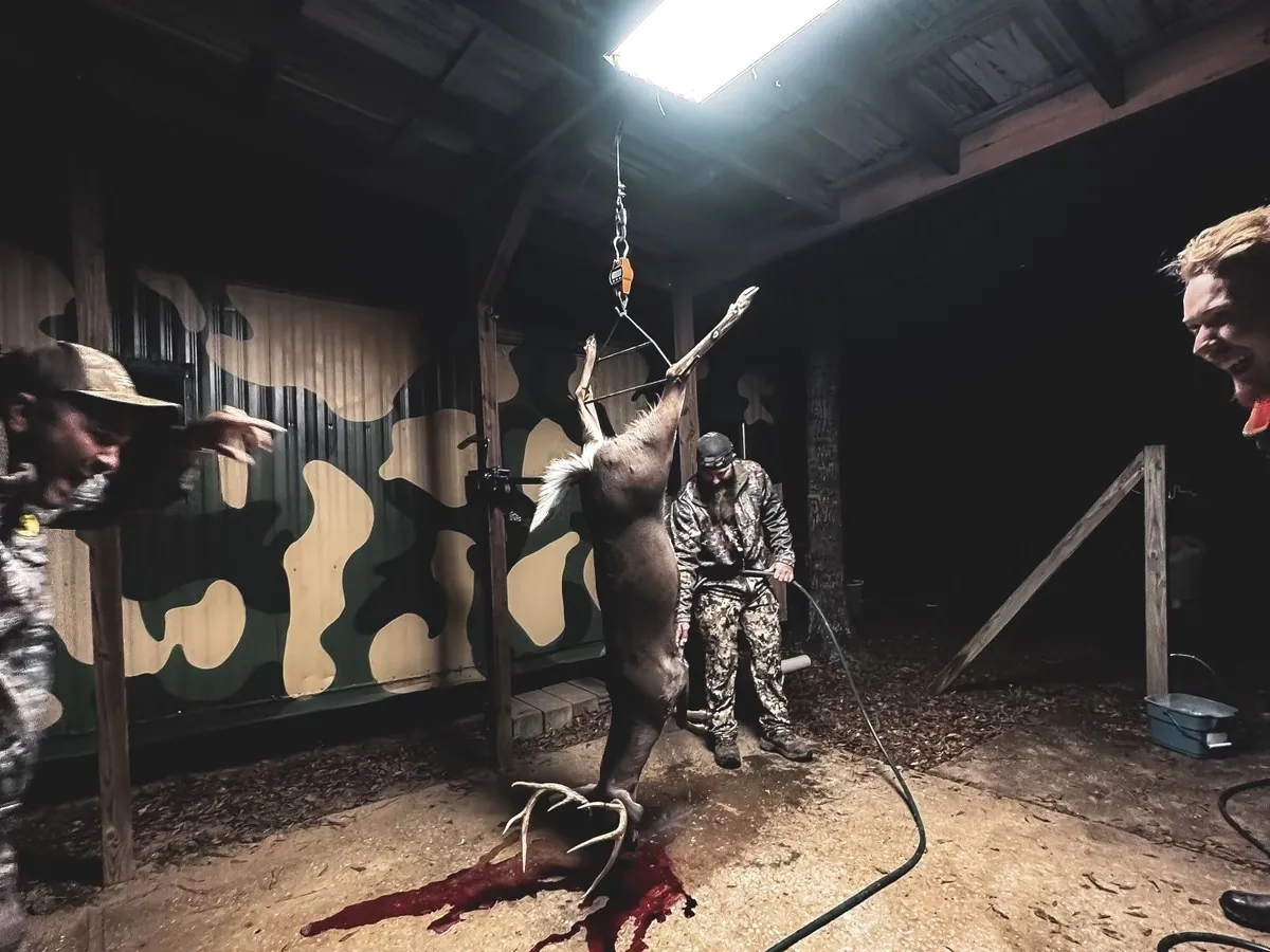 Hunters working in the skinning shed under a work light after a hunt
