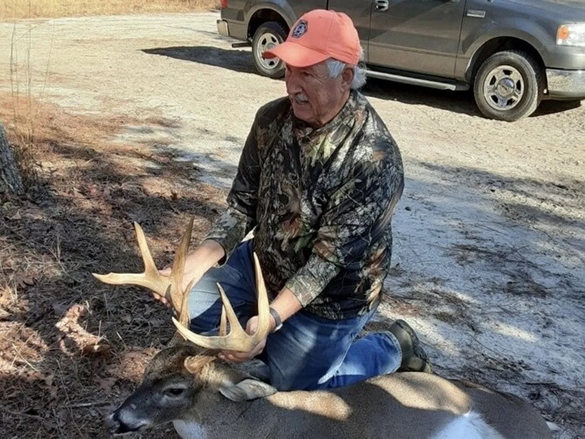 A hunter kneeling behind a heavy-racked whitetail buck taken in North Carolina