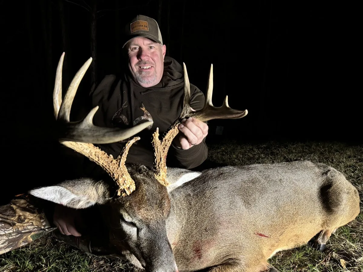 A hunter behind a heavy-racked whitetail buck taken after dark in South Carolina