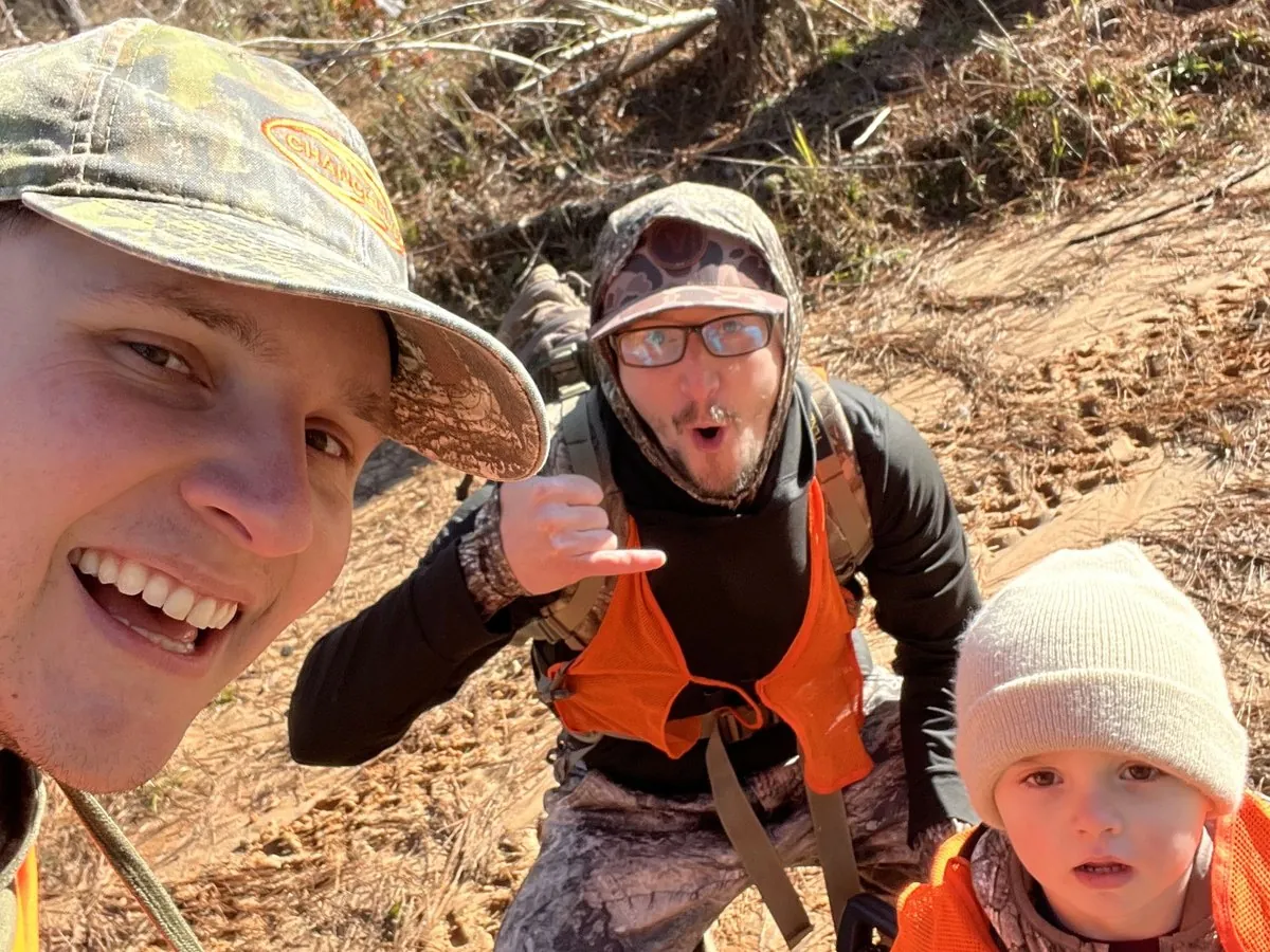 Three hunters in blaze orange on a hunt, including a young child