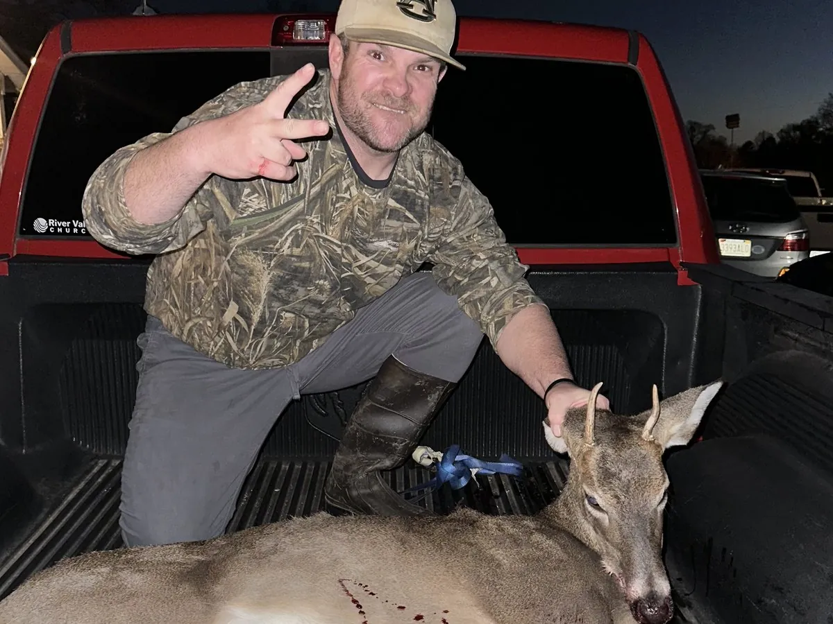 A hunter in a truck bed with a whitetail buck at dusk