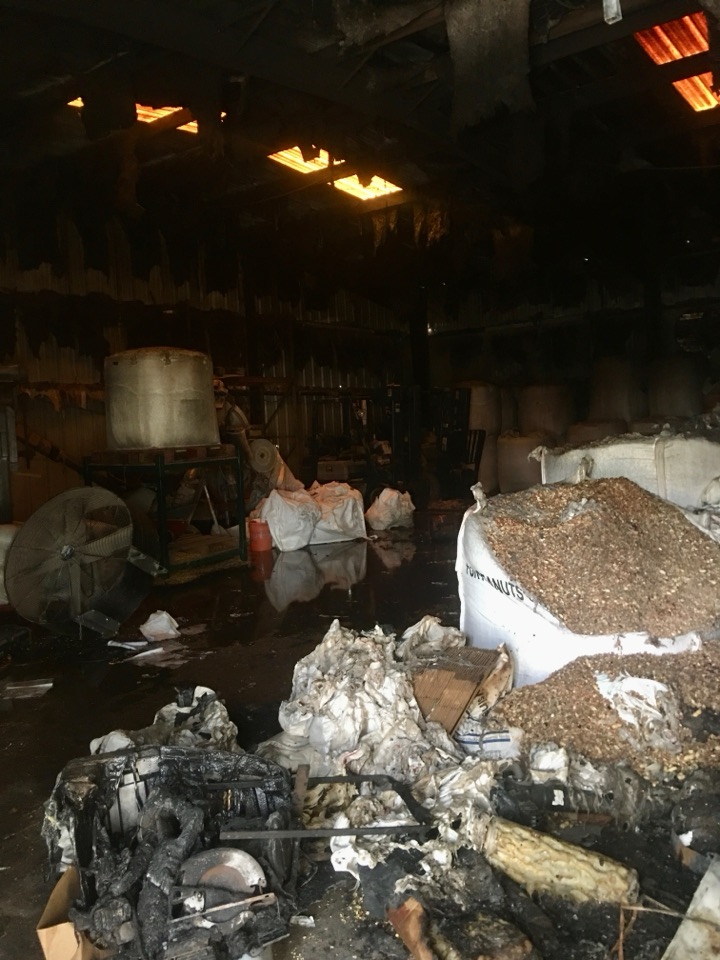 Inside the facility after the October 2020 fire — charred walls and burned totes of feed.