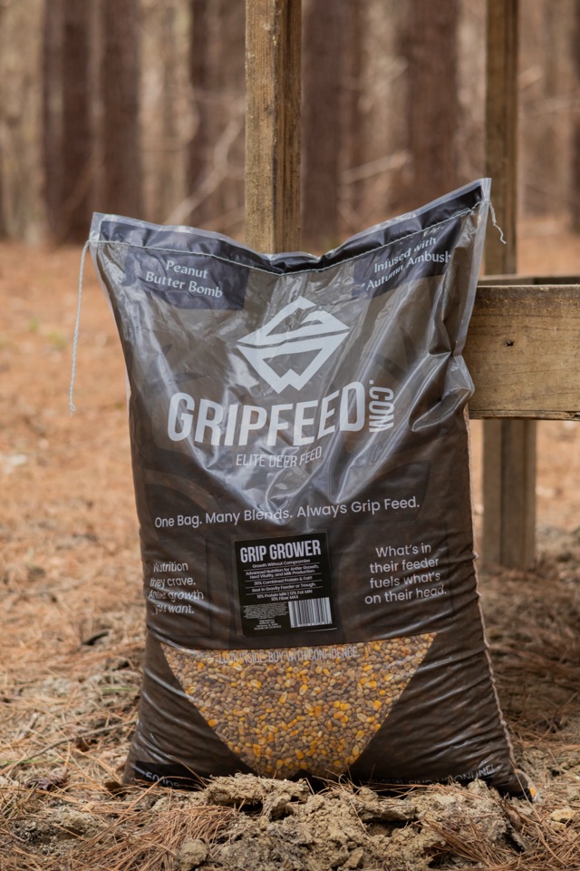 A bag of Grip Grower leaning against a wooden feeder in the pines.