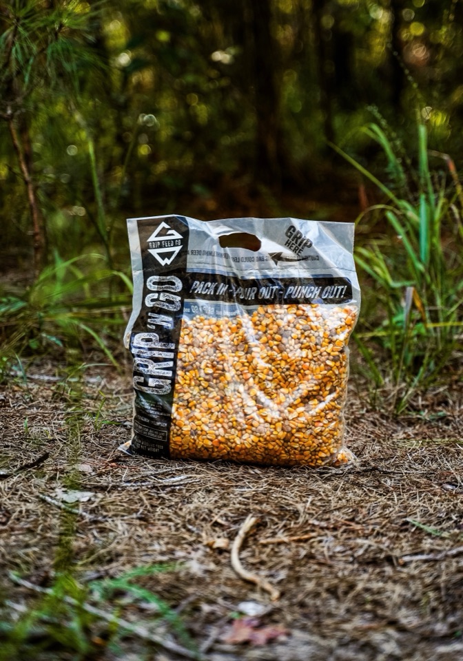 A Grip 'N Go bag of corn and pellets sitting on the pine straw.