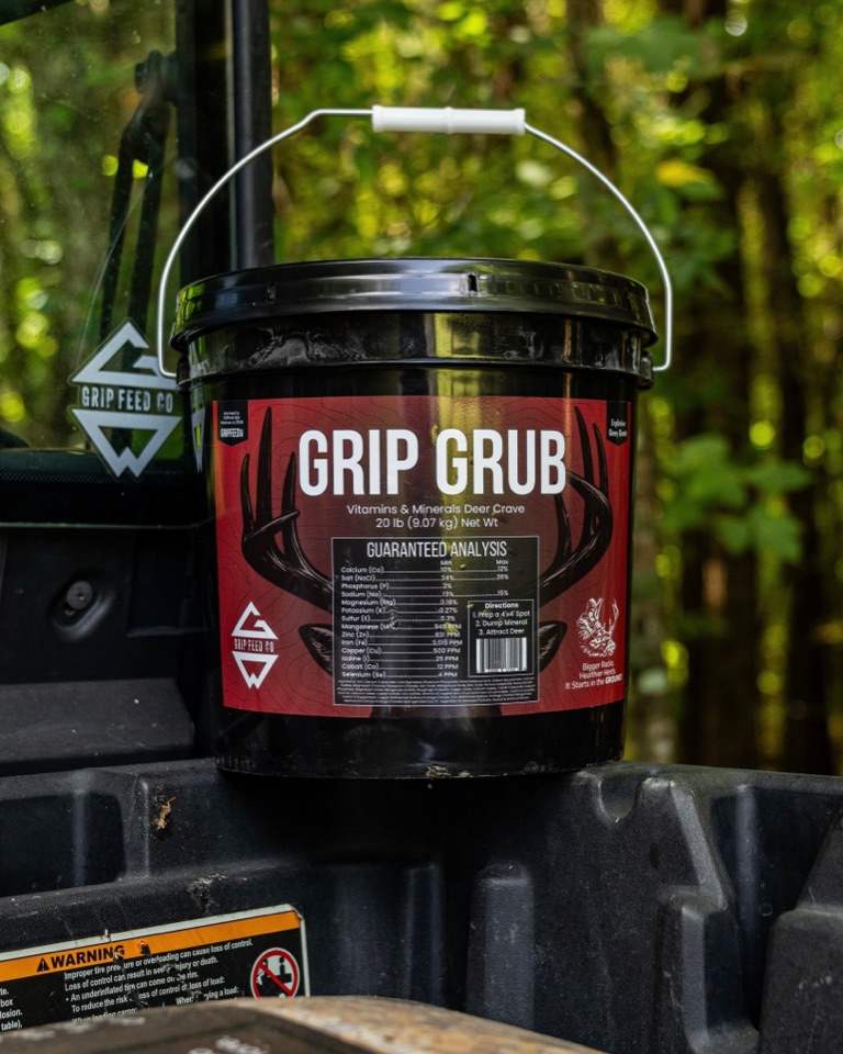 A Grip Grub mineral bucket riding in the bed of a UTV.
