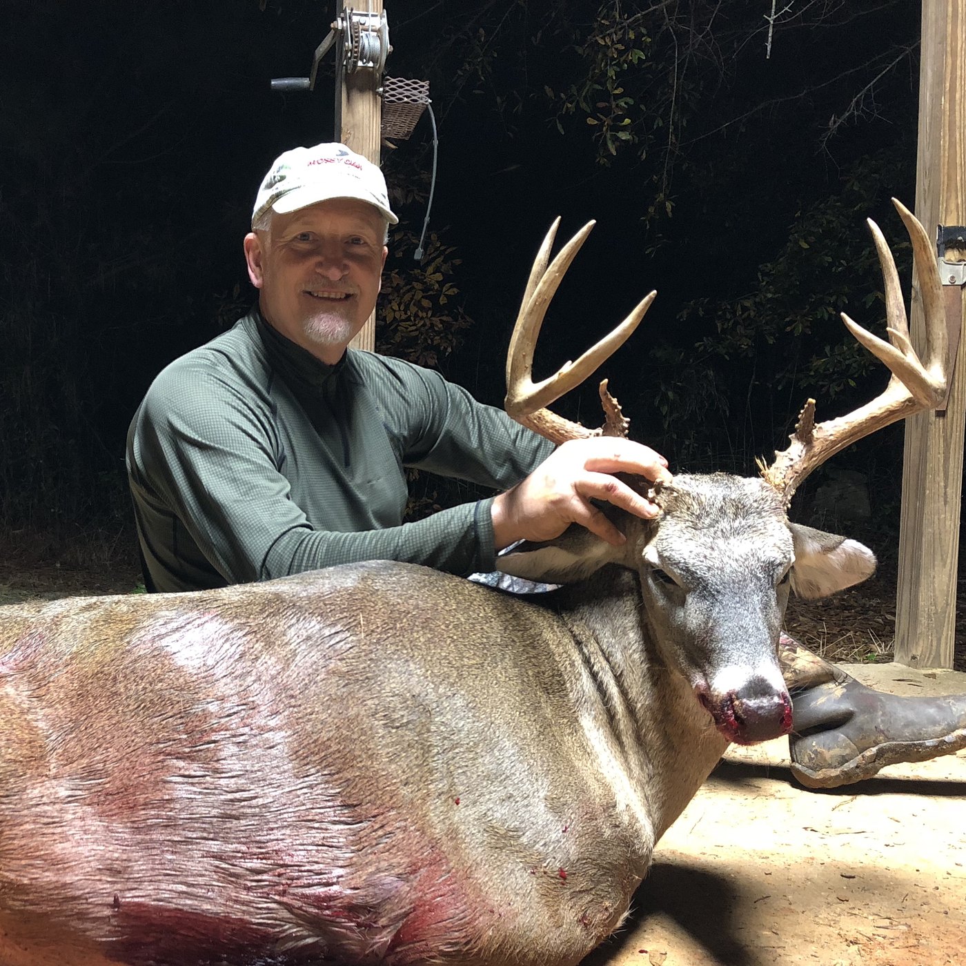 Hunter kneeling with a tall-tined buck on a tailgate