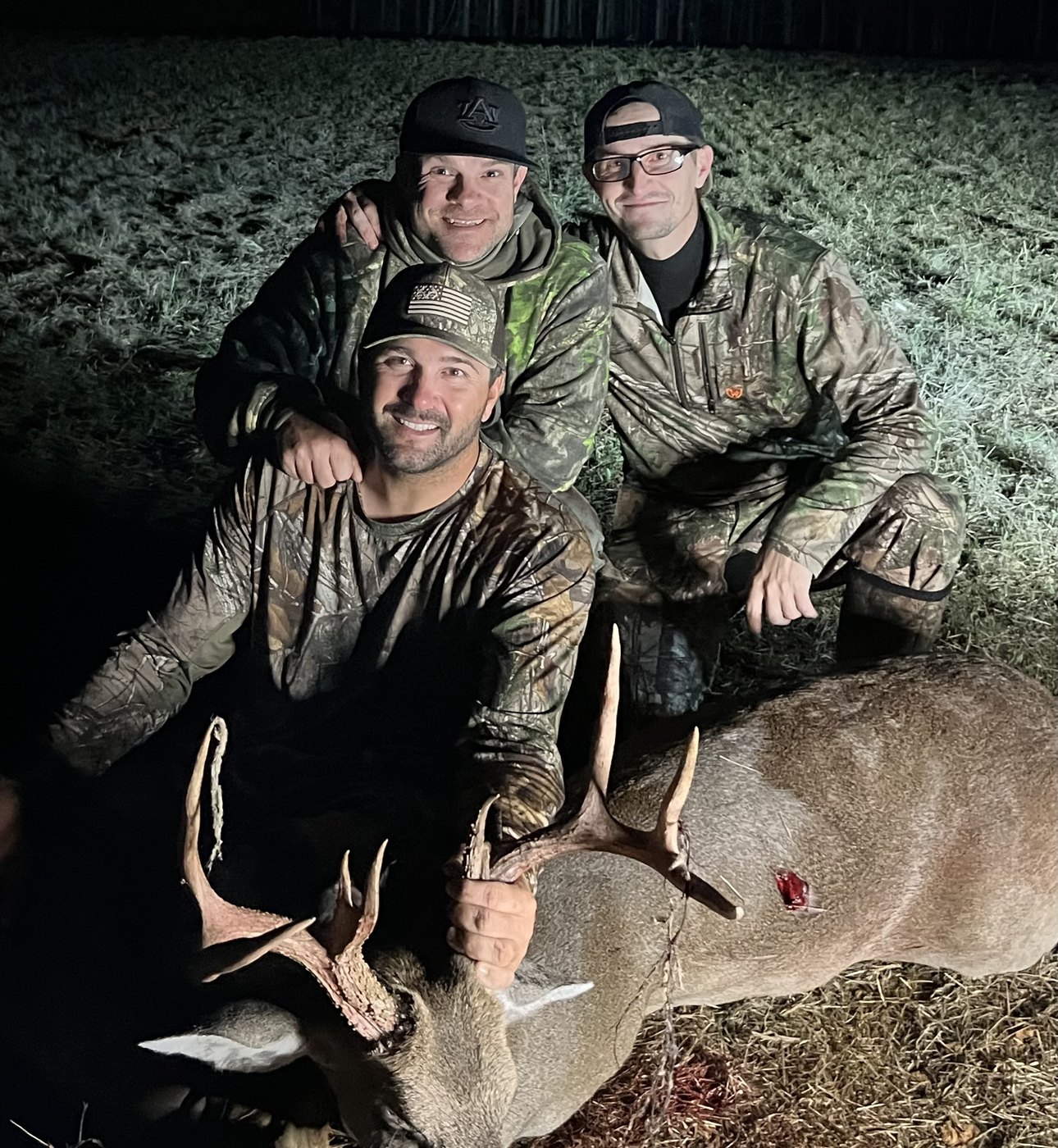 Three hunters with a buck taken after dark