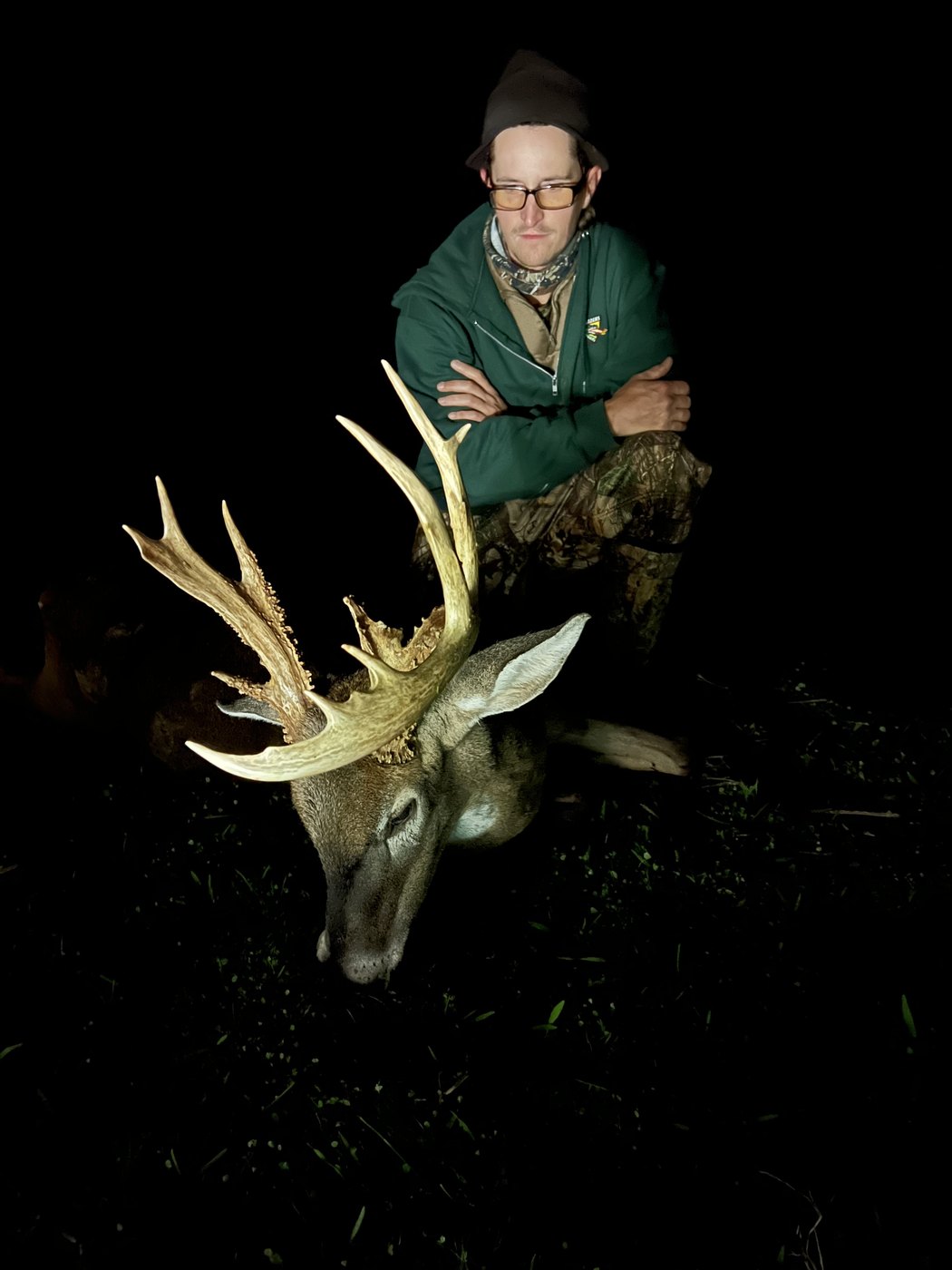 Hunter behind a tall-racked buck in the dark