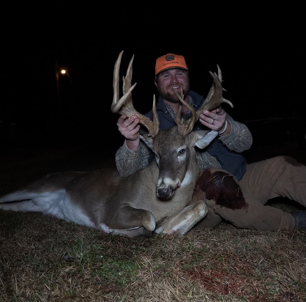 Hunter in a blaze cap with a buck taken after dark