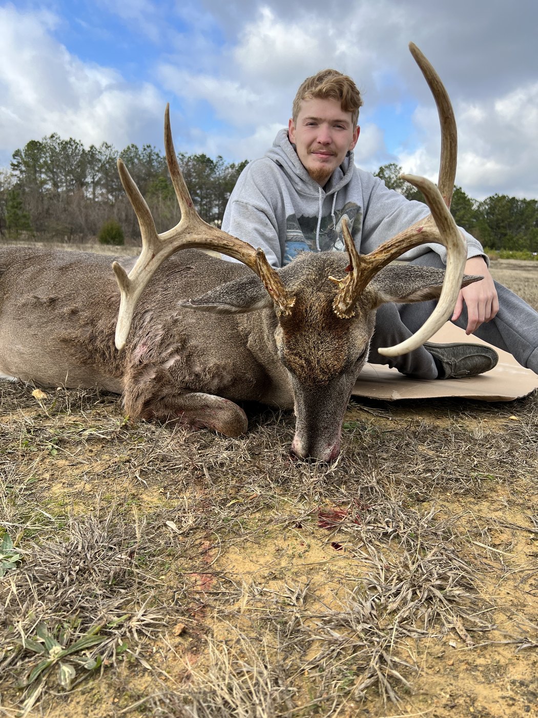 Hunter kneeling with a wide whitetail buck in a barn