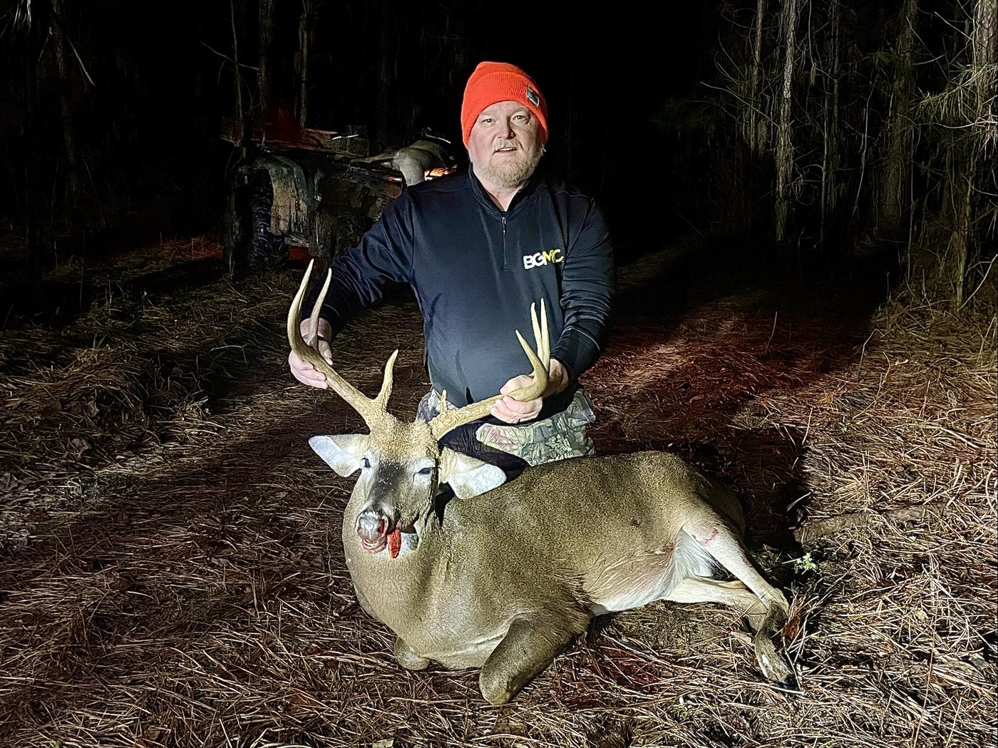 Hunter in a blaze cap with a buck taken after dark