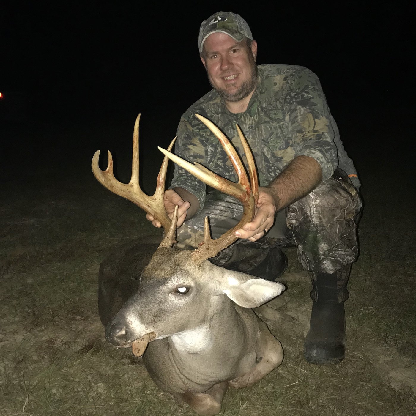 Hunter with a tall-tined buck photographed at night