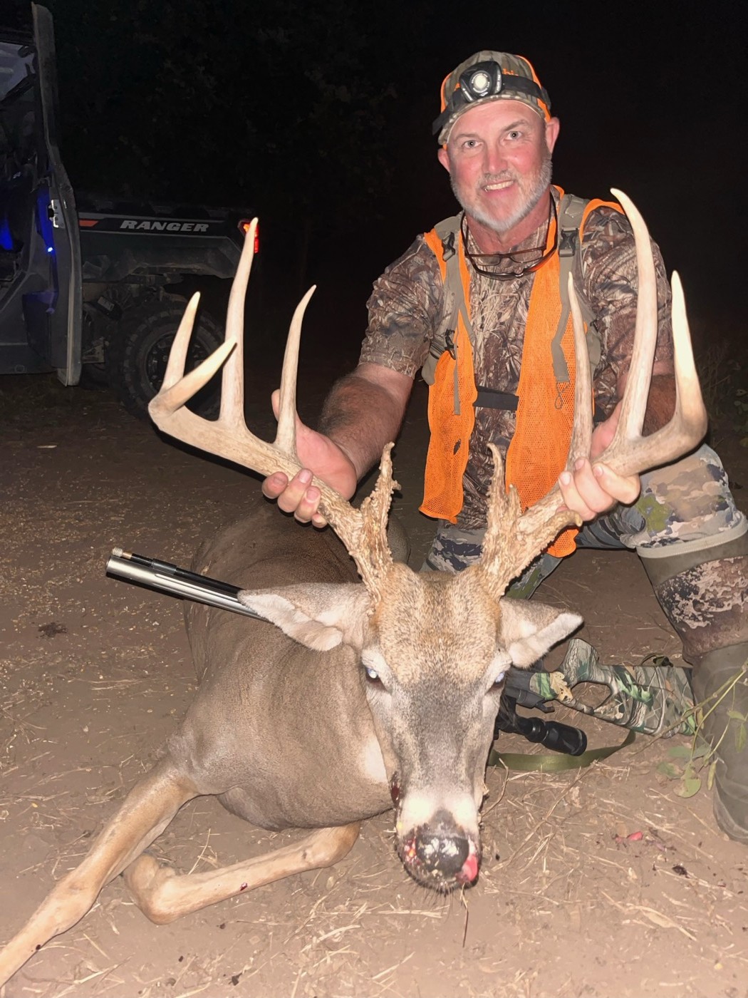Hunter in blaze orange with a wide-racked whitetail buck