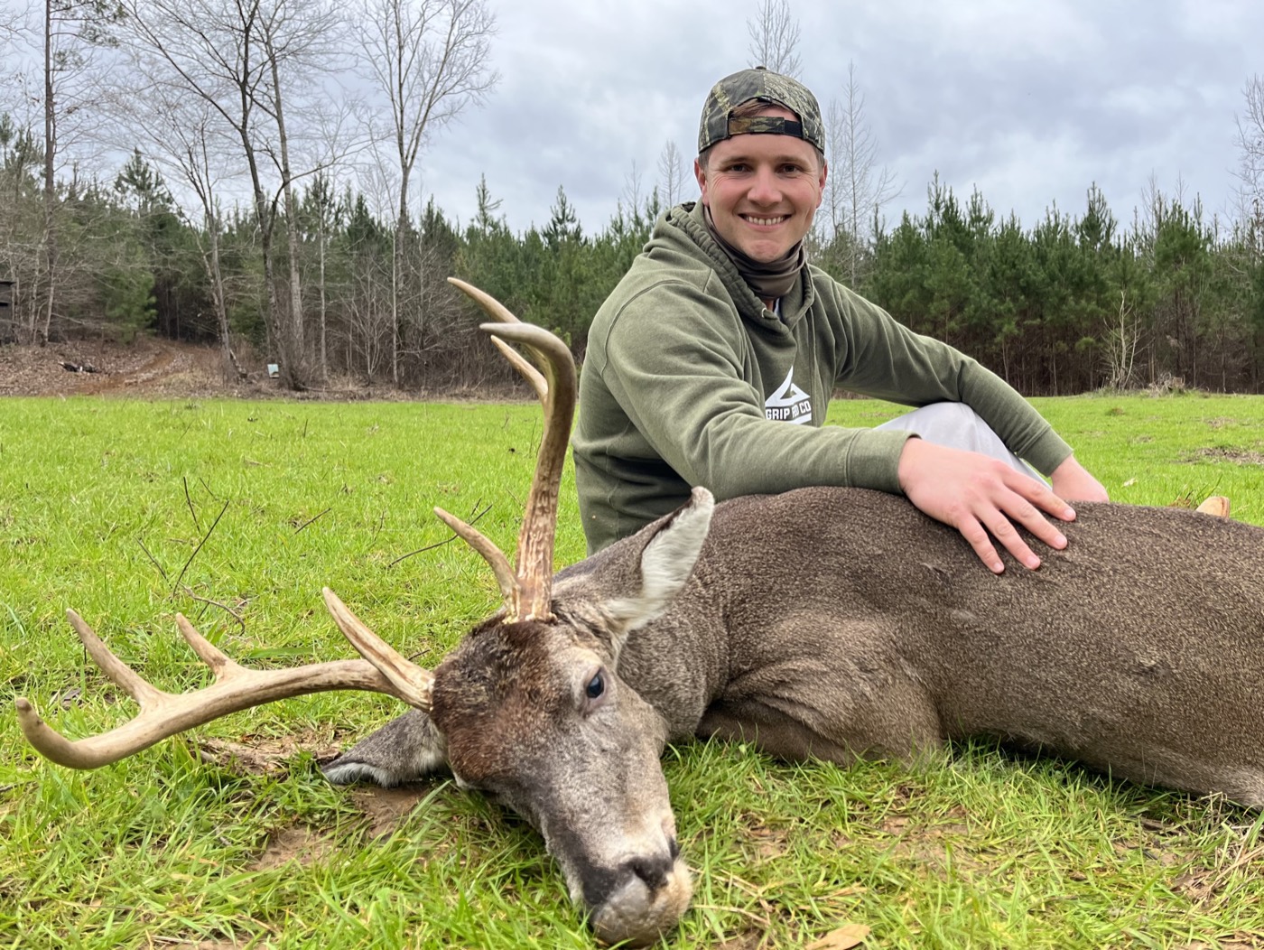 Hunter in Grip Feed gear with a whitetail buck on a green field