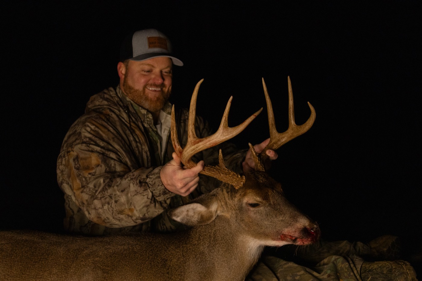 Hunter with a mature whitetail buck photographed at night